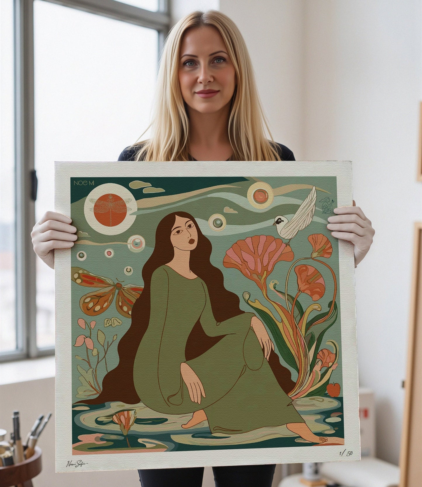 Noemi Safir artist holding a limited edition print of a woman sitting among flowers and nature elements. Vibrant, fade‑resistant inks for long‑lasting beauty by NOE MI