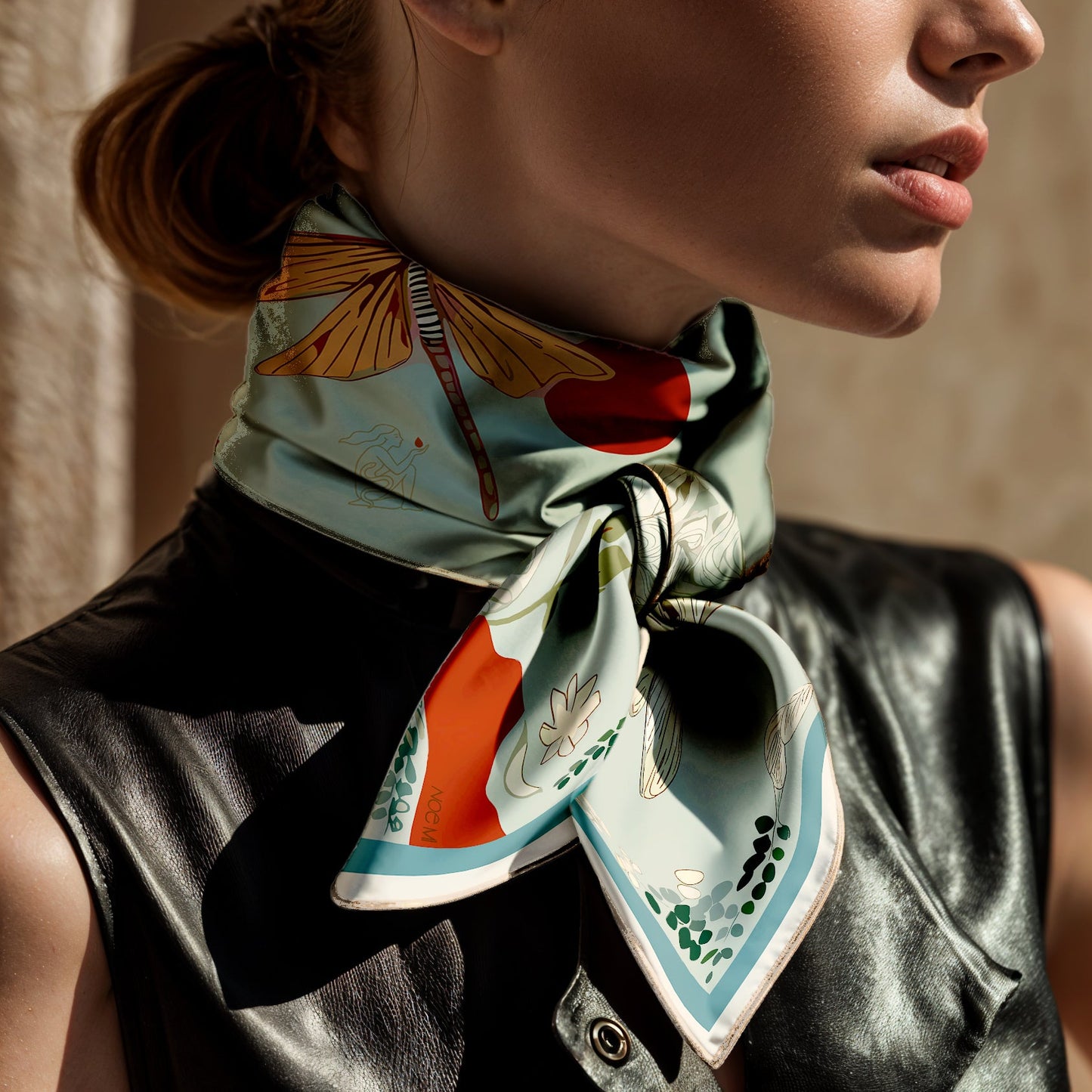 Woman wearing a colorful luxury art silk twill scarf by NOE MI with butterfly design on a neutral background