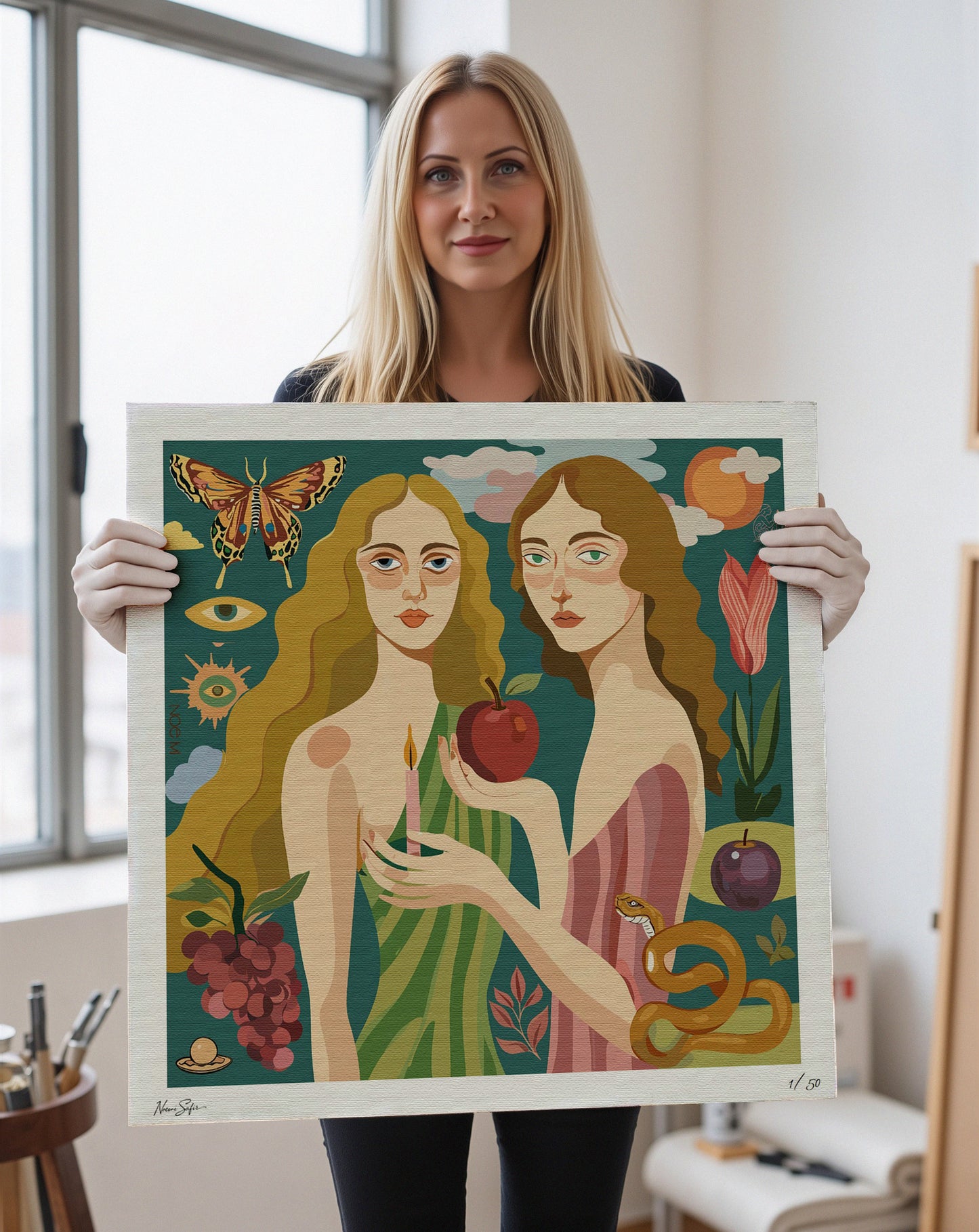 Woman holding a framed Limited Edition wall art print of two women with a snake and apple