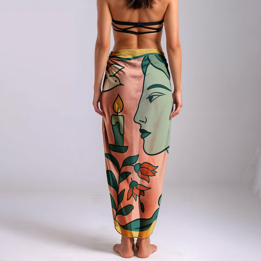 Woman wearing a colorful silk or chiffon pareo/sarong with artistic design on a plain background