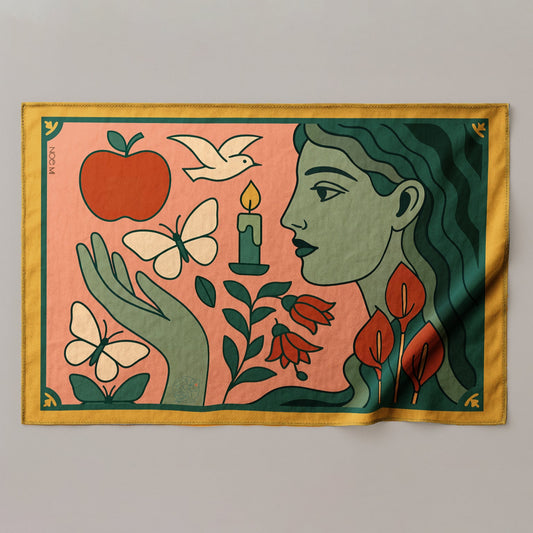 a colorful silk or chiffon pareo/sarong with a stylized face, hand, and nature elements on a pink background.