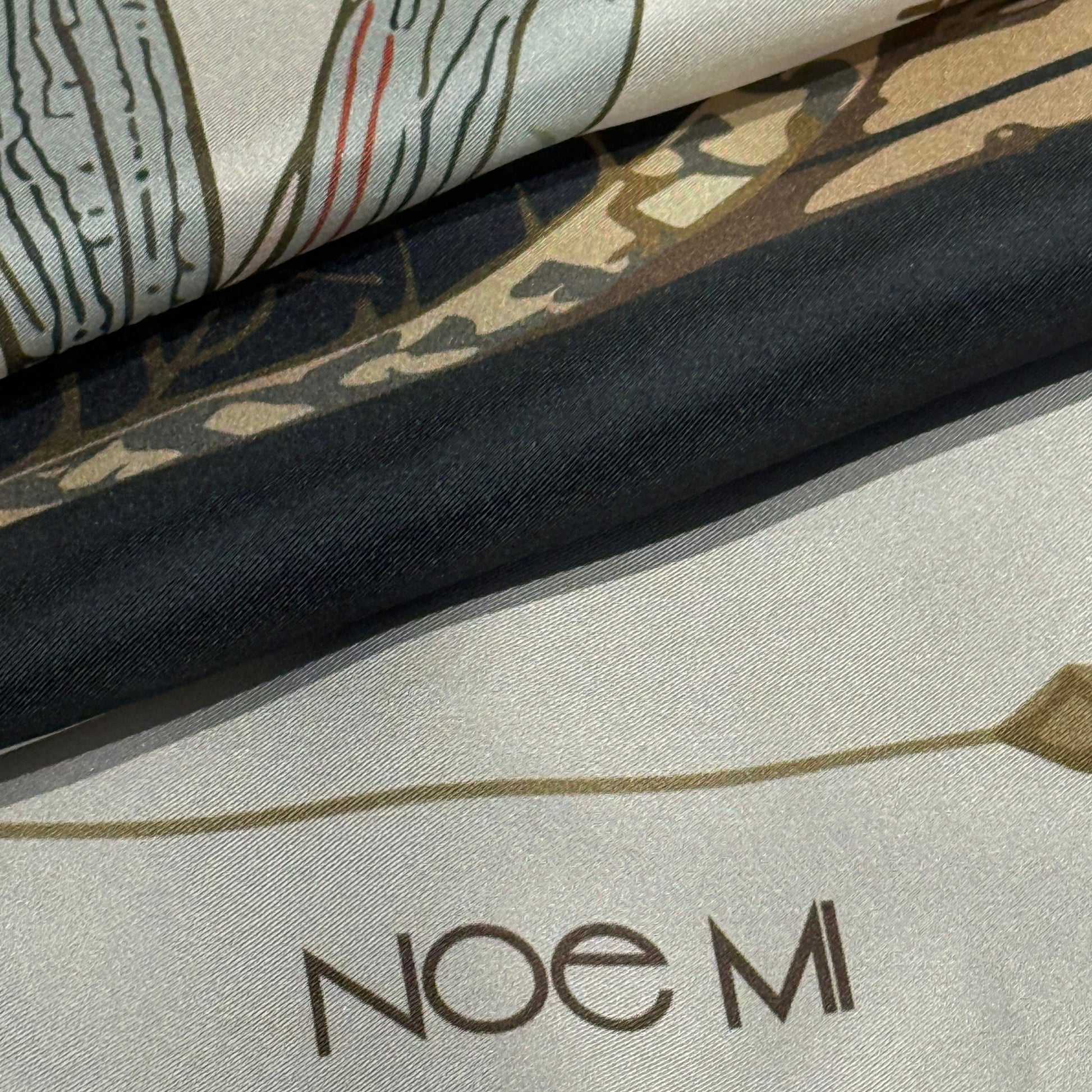High-end silk scarf by NOE MI, The Navigator print featuring symbolic feminine portrait, wheel, dragonflies, and surreal decorative motifs.