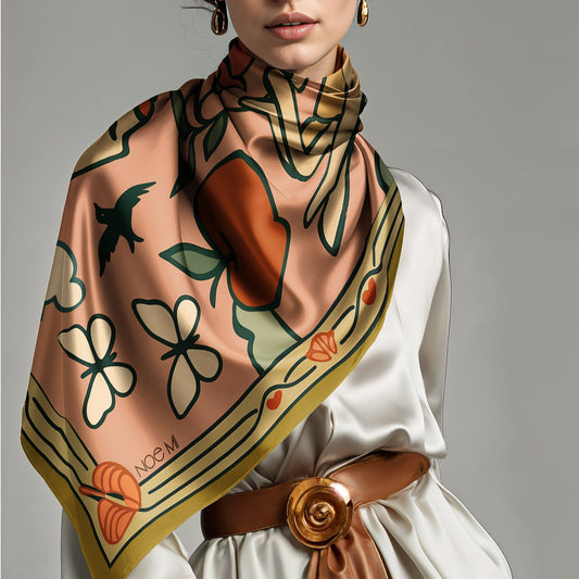 Person wearing a colorful patterned Square NOE MI luxury art silk twill scarf in pink and gold 