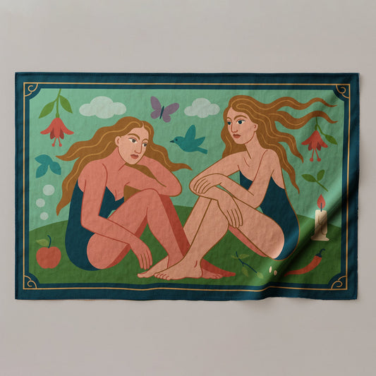 a colorful silk or chiffon pareo/sarong with an illustration of two nude figures sitting on a grassy field with flowers and birds.