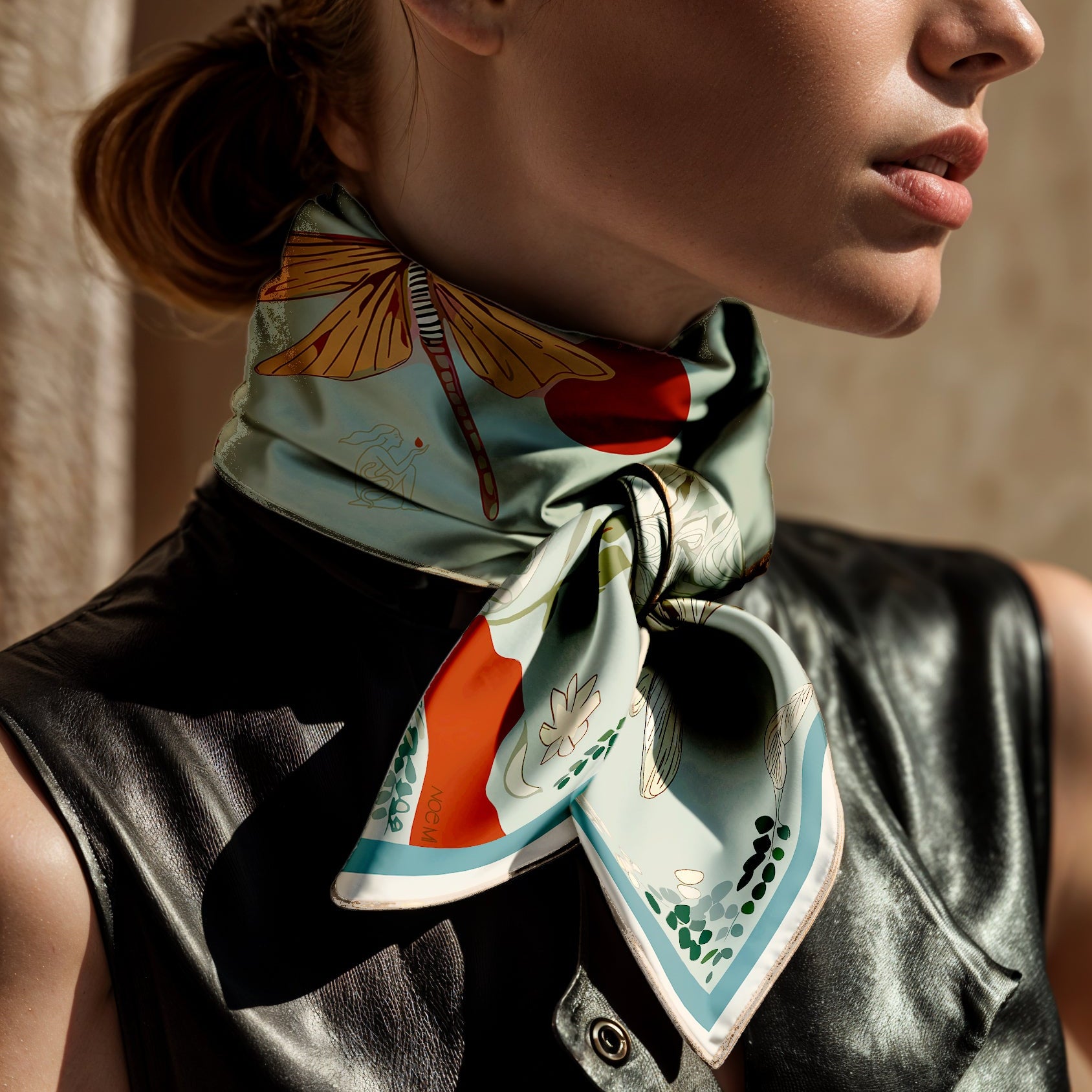 Woman wearing a colorful luxury art silk twill scarf by NOE MI with butterfly design on a neutral background